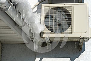 An outdoor air conditioner unit installed on the outer wall of a residential building close-up. Operation of the air conditioner