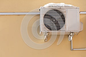 An outdoor air conditioner unit installed on the outer wall of a residential building. The fan and the radiator grille of the air