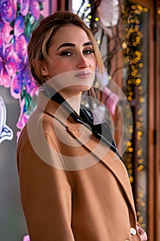 Outdoor autumn fashion portrait of elegant, luxury woman wearing trendy midi beige, black leather suit, camel color coat, holding