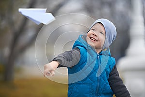 Outdoor autumn portrait of the preschool boy launching a paper plane