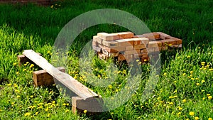 Outdoor Backyard with green grass and dandelions around handmade grill from red bricks and old brench near it