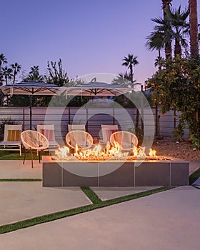 Outdoor backyard patio at night with a fireplace and chairs