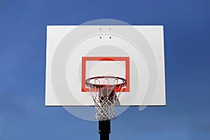 Outdoor Basketball Hoop and Backboard Isolated Against Blue Sky photo
