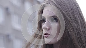 Outdoor beauty portrait of young brown haired girl looking aside over blurred city line background. Action. Close up for