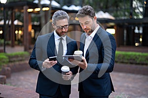 Outdoor business meeting. Business meeting. Businessmen talking. Two businessmen discussing using tablet on coffee break