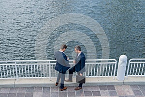 Outdoor business meeting. Photo of business partners talk conversation outdoor. Two handsome businessmen in suits