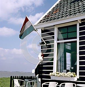 Outdoor cafe with empty chairs and Dutch National Flag