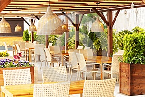 Outdoor cafe with wicker furniture and lamps. Blurred image