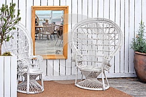 Outdoor cafe with wicker furniture, photo area with mirror and plants in clay pots.