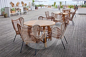 Outdoor cafe with wicker furniture and wooden tables. Empty tables in outdoor sidewalk cafe or restaurant. Touristic setting, cafe