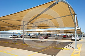 An outdoor car park with shade canopies in a shopping centre.