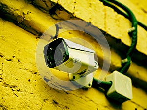 Outdoor CCTV camera mounted on the wall of an old brick house. New camera with protective films on the lens. Video surveillance on