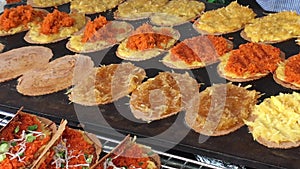 Outdoor chef cooking traditional Thai appetizer steamed rice parcels with sweetened ground peanut filling named sweetmeat