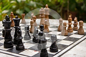 Outdoor chessboard with black and yellow figures with unfocused background. Competition and strategy concept. Intelligent sport.