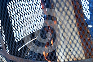 Outdoor chimney with steel grille and firewood in the burning process