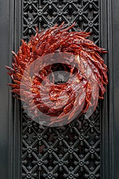 Outdoor Christmas wreath made of dried red hot chili peppers hanging at entrance door