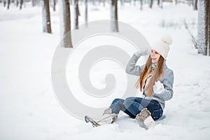 Outdoor close-up portrait of young beautiful happy smiling girl, wearing stylish knitted winter hat and gloves. Model expressing j