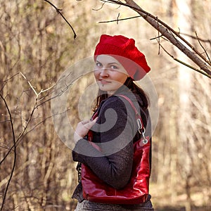 Outdoor close up portrait of young beautiful happy smiling girl wearing french style red knitted beret