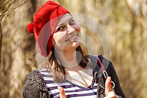 Outdoor close up portrait of young beautiful happy smiling girl wearing french style red knitted beret