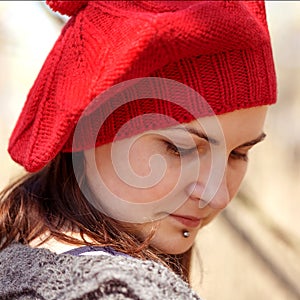 Outdoor close up portrait of young beautiful happy smiling girl wearing french style red knitted beret