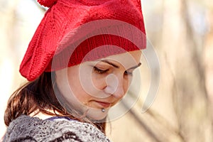 Outdoor close up portrait of young beautiful happy smiling girl wearing french style red knitted beret