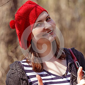 Outdoor close up portrait of young beautiful happy smiling girl wearing french style red knitted beret