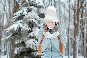 Outdoor close-up portrait of young beautiful happy smiling girl, wearing stylish knitted winter hat and gloves. Model expressing j