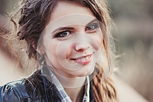 Outdoor close up portrait of young smiling beautiful woman with natural make up