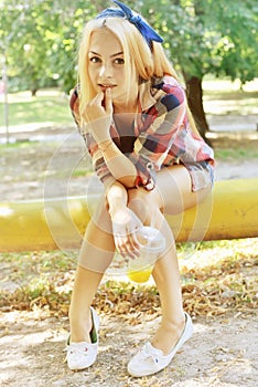 Outdoor colorful summer closeup photo of young pretty blonde happy smiling girl with coctail in hand having fun. Fashion lifestyle