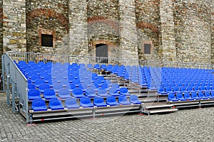 Outdoor concert venue with empty blue seats rows, mobile metal structure with plastic seats