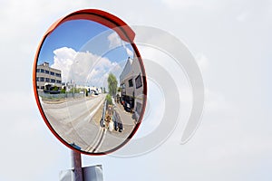 Outdoor convex safety mirror hanging on wall with reflection of an urban roadside view of cars parked along the street photo