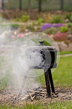 Outdoor cooking, smoky cast iron pot. Vertical shot.