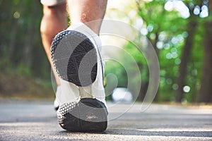 Outdoor cross-country running in concept for exercising, fitness and healthy lifestyle. Close up of feet of young runner