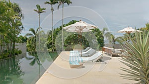 Outdoor deck, terrace with sun bed, umbrellas and towels near the swimming pool, next to the beach front