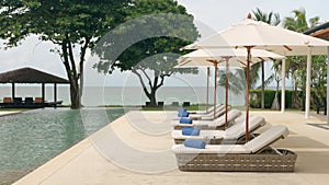 Outdoor deck, terrace with sunbed, umbrellas and towels near the swimming pool, next to the beach front