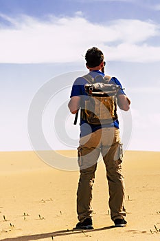 Outdoor desert adventure and alternative tourism and tourist activity with standing man from back with backpack looking a sand