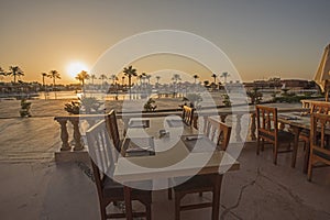 Outdoor dining table with sunset in tropical hotel resort