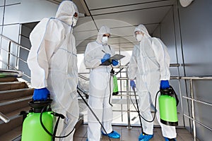 Outdoor disinfection by cleaning workers in hazmat suits photo