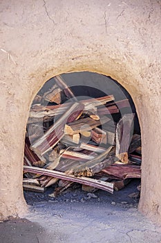 Outdoor Earth Oven in mud pueblo - Horno - closeup filled with split cedar firewood - selective focus photo