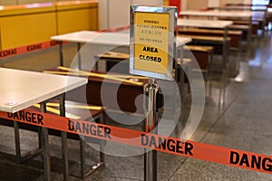 Outdoor eatery placed a closed sign for a pandemic lockdown period, barred the area with a barricade red tape