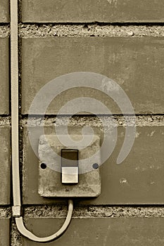 Outdoor electric equipment control industrial button switch wire cable closeup, old aged weathered grungy brick wall background