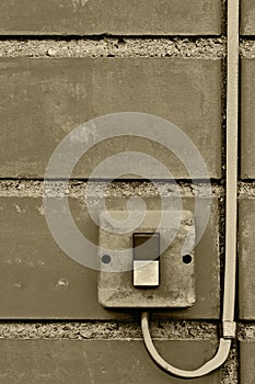 Outdoor electric equipment control industrial button switch wire cable closeup, old aged weathered grungy brick wall background