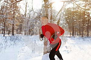 Outdoor endurance exercises. Athletic mature man doing TRX fitness workout at winter park, copy space