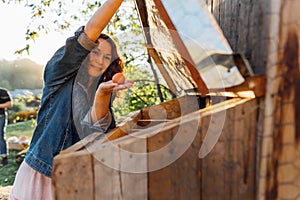 Outdoor enthusiast in denim smiles upon finding an egg in the chicken nest