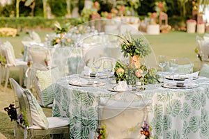 Outdoor event in progress, with an arrangement of tables and chairs set against a lush green garden