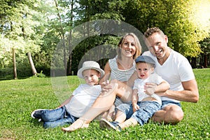 Outdoor family portrait of happy family of four in a green summer home garden