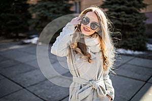 Outdoor fashion closeup portrait of young pretty woman in sunglases walking on street