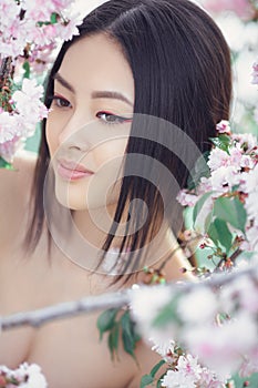 Portrait of a beautiful fantasy asian girl outdoors against natural spring flower background.