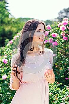 Outdoor fashion photo of beautiful young happy smiling woman surrounded by flowers. Spring blossom