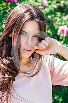 Outdoor fashion photo of beautiful young happy smiling woman surrounded by flowers. Spring blossom